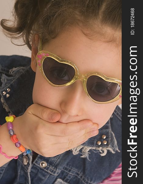 Young girl with sunglasses and hand shutting mouth
