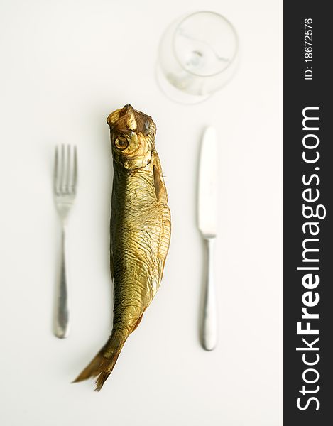 dried aringa fish isolated on white with fork knife and glass