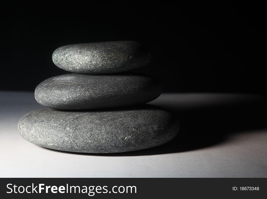 Three stones balancing on each other and black backdrop. Three stones balancing on each other and black backdrop