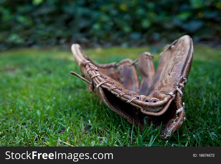 Old worn out well-loved baseball glove lying in the grass. Old worn out well-loved baseball glove lying in the grass