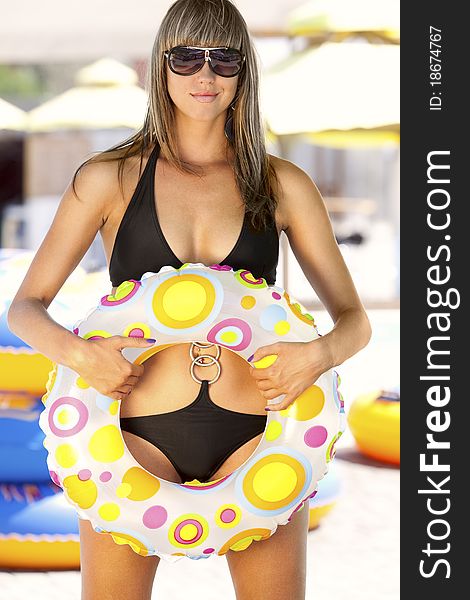 Beautiful model in black swimsuit, with multicolored inflatable ring. Beautiful model in black swimsuit, with multicolored inflatable ring