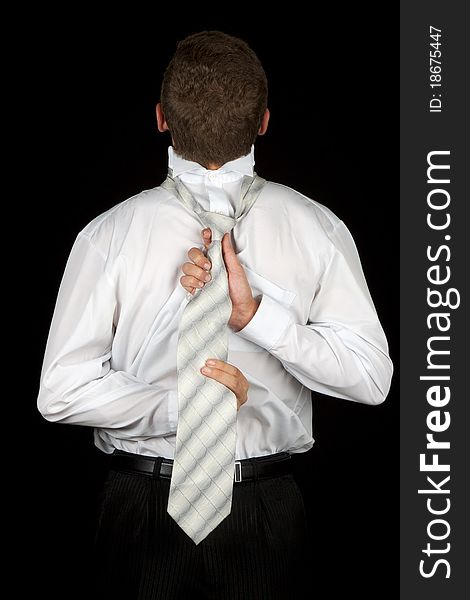 Businessman back, tying tie, concept help assistance, isolated on black, low key. Businessman back, tying tie, concept help assistance, isolated on black, low key.
