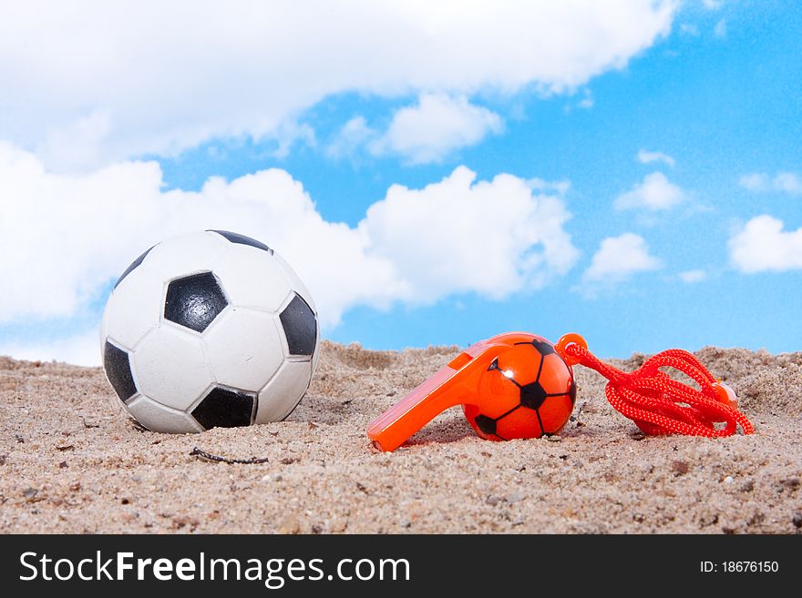 Beach soccer against a blue sky and a referee whistle