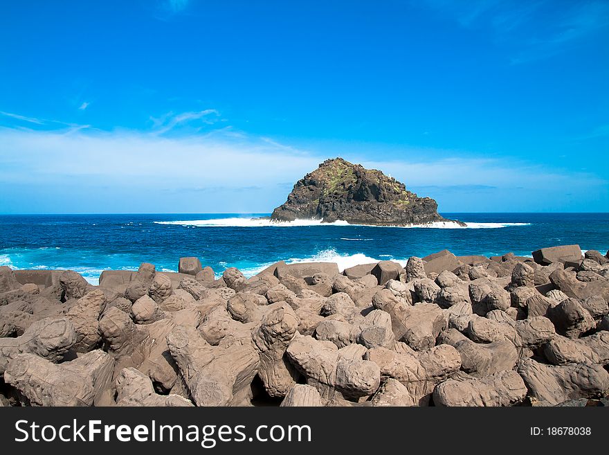 A view of an island in tenerife with rocks in the foreground. A view of an island in tenerife with rocks in the foreground