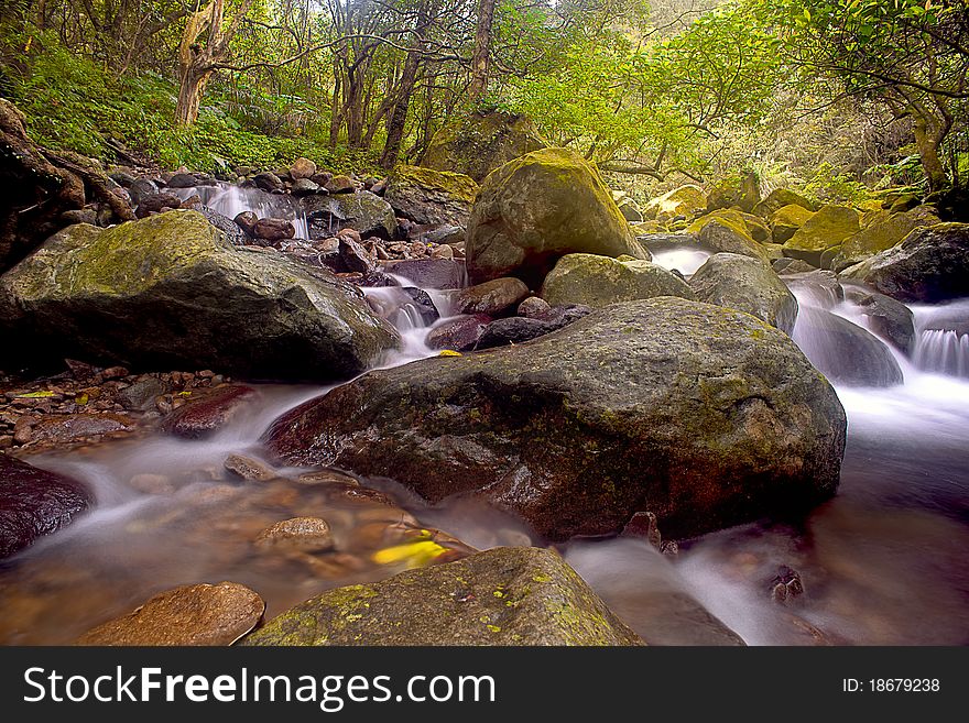 Cascade falls over old plum river with rocks