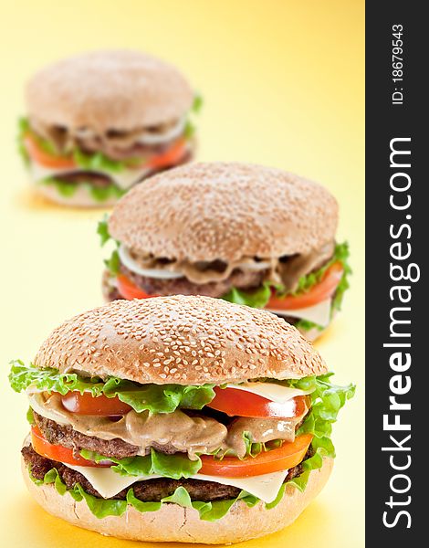 Three delicious hamburger on a yellow background