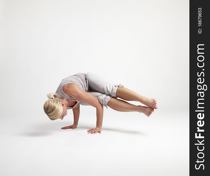 Young woman doing yoga exercise on white background