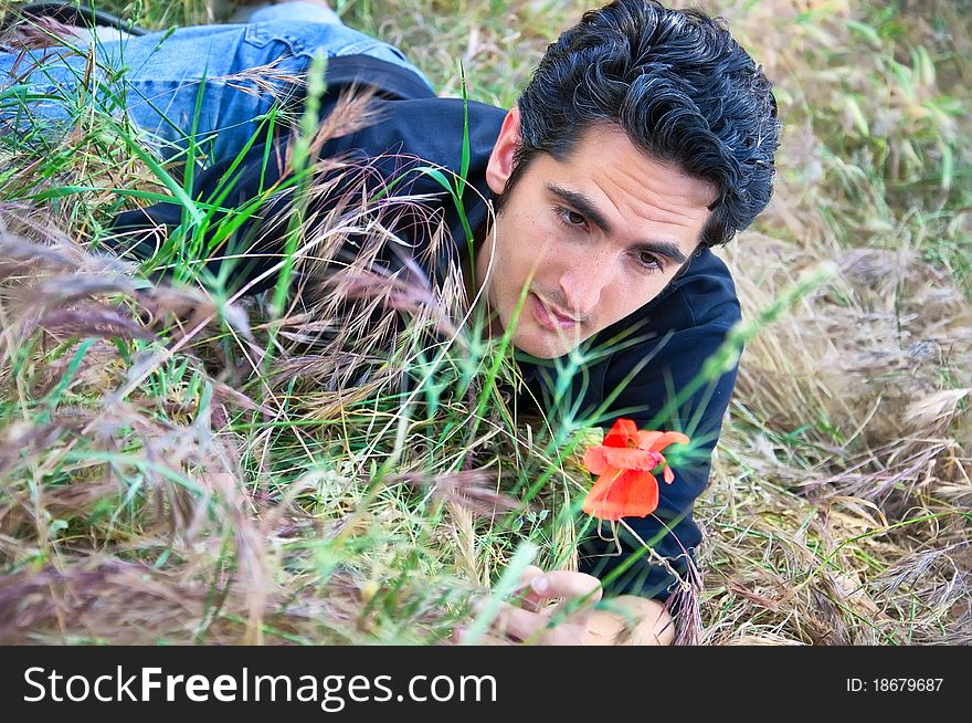 Young man lying on the grass looking the flower. Young man lying on the grass looking the flower
