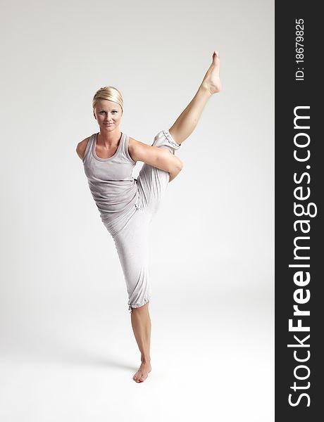 Young woman doing yoga exercise on white background