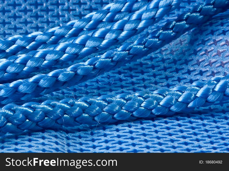 A background of a closeup of blue nylon fabric and shiny blue rope. A background of a closeup of blue nylon fabric and shiny blue rope