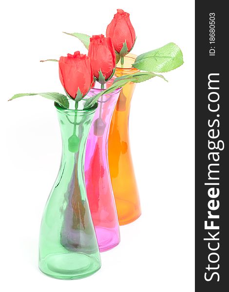 Glass color vases with roses isolated on white background