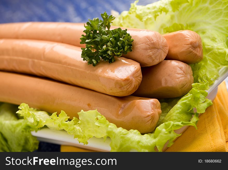 Photo of delicious german sausages on green fresh lettuce with parsley