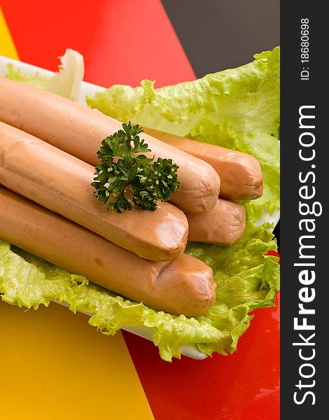 Photo of delicious german sausages on green fresh lettuce with parsley