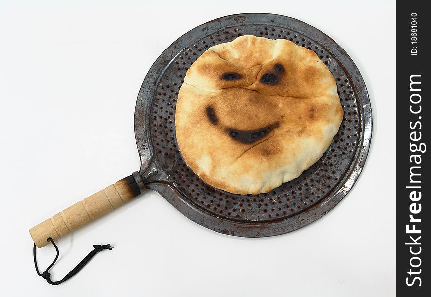 A shot of a rounded bread that is burnt in some parts of it that made it look like a smiley face. A shot of a rounded bread that is burnt in some parts of it that made it look like a smiley face