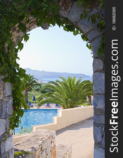 Swimming pool with sunbed seen through arc. Swimming pool with sunbed seen through arc