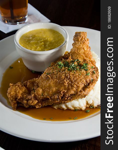 Fried chicken over potatoes with creamed corn. Fried chicken over potatoes with creamed corn