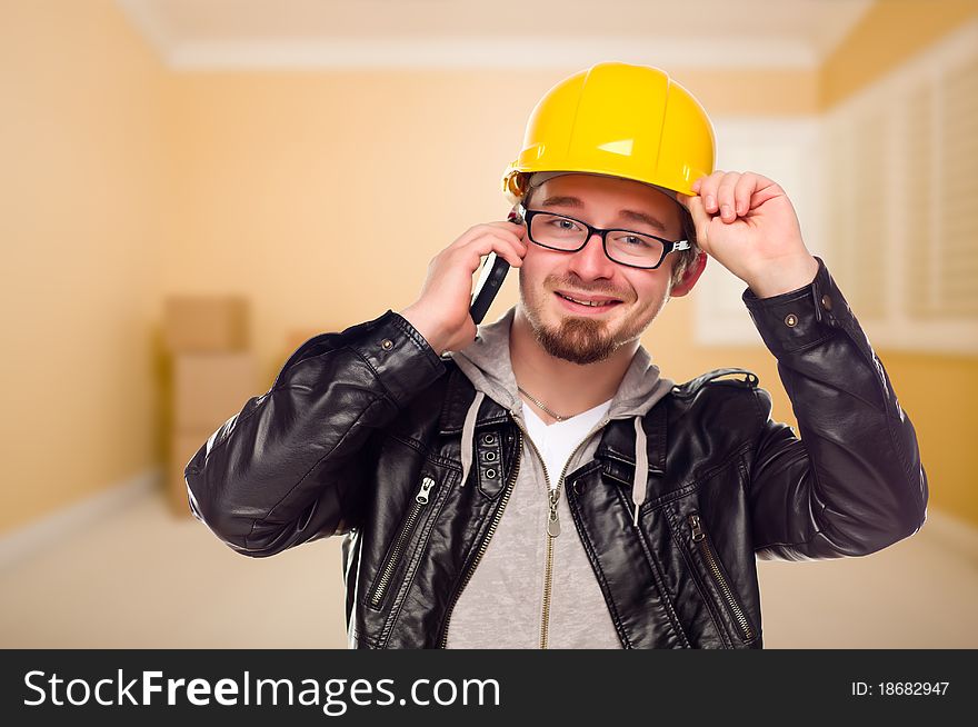 Young Contractor Wearing Hard Hat on Cell Phone Inside Empty House. Young Contractor Wearing Hard Hat on Cell Phone Inside Empty House.