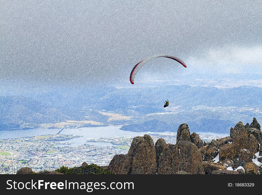 A paraglider hovers over Mount Wellington in Tasmania while it snows. A paraglider hovers over Mount Wellington in Tasmania while it snows.
