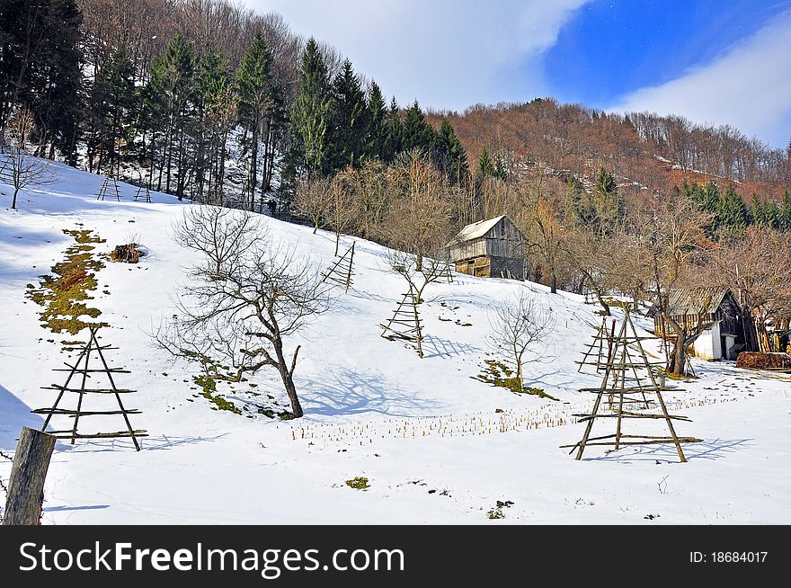 Rural landscape with wooden house on the snowy hill