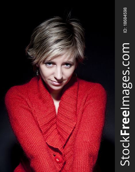 Portrait of attractive woman in red pullover on black background