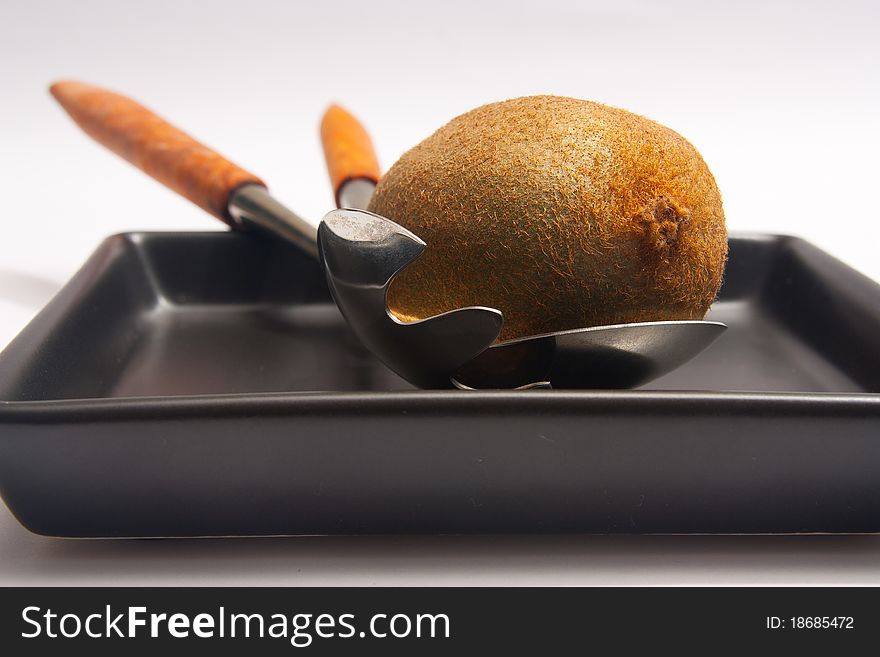 Kiwi on black plate with salad pickers