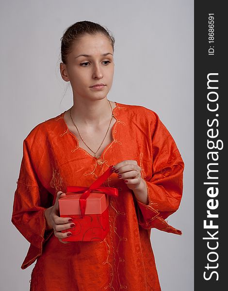 Thoughtful girl in an orange dress opens a gift