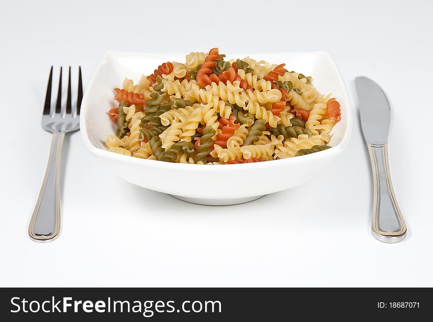 Bowl full with hairsprings of pasta of wheat of colors and cutleries. Bowl full with hairsprings of pasta of wheat of colors and cutleries