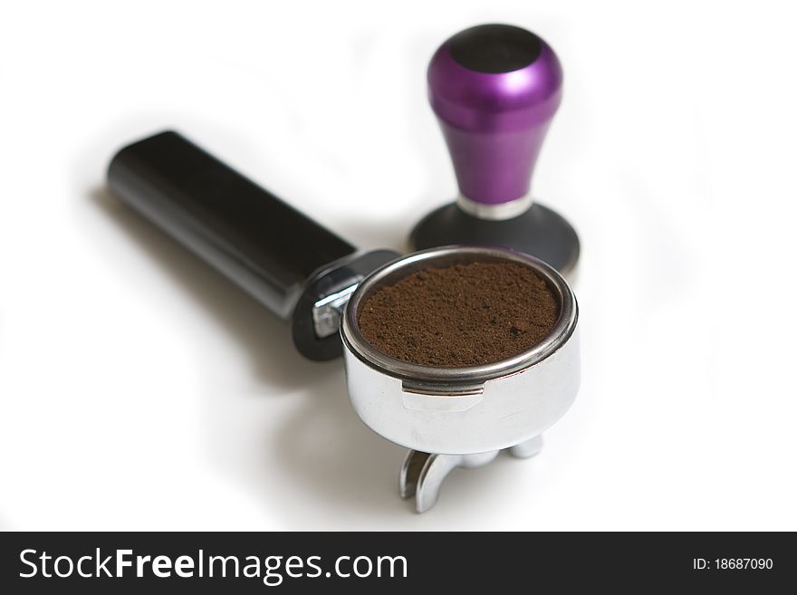 Ground coffee in a portafilter and a coffee tamper isolated on a white background. Ground coffee in a portafilter and a coffee tamper isolated on a white background
