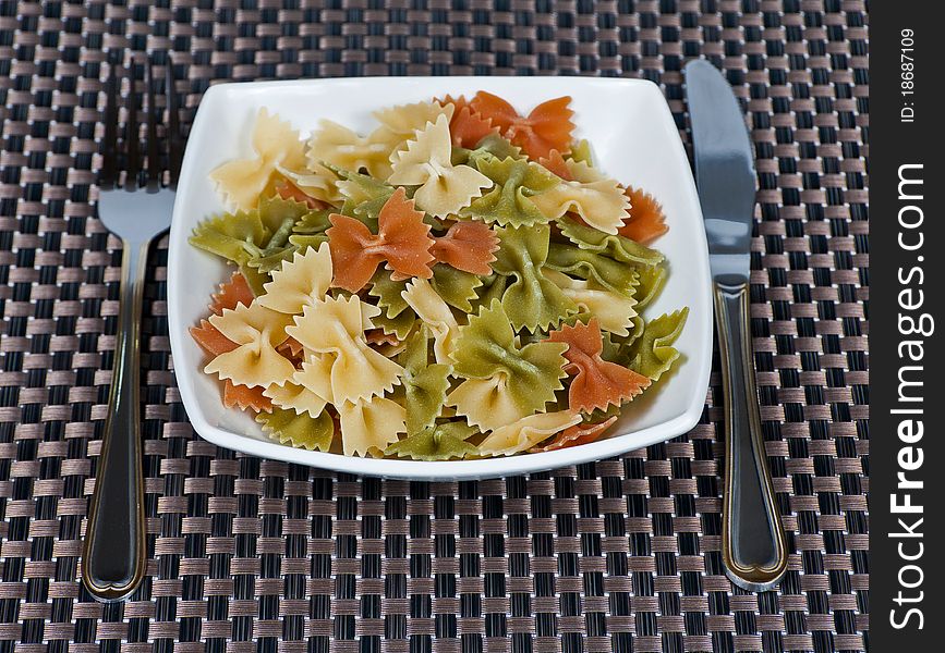 Bowl full with hairsprings of pasta of wheat of colors and cutleries. Bowl full with hairsprings of pasta of wheat of colors and cutleries