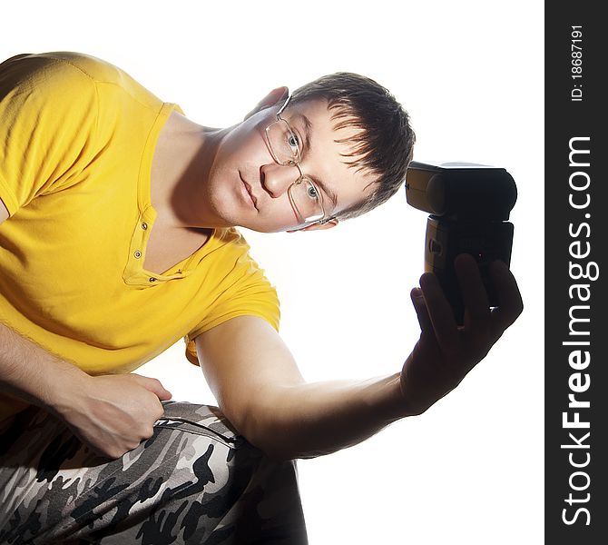 Guy with glasses and yellow shirt. Illuminates himself flash in his left hand. Isolated on a white background. Guy with glasses and yellow shirt. Illuminates himself flash in his left hand. Isolated on a white background.