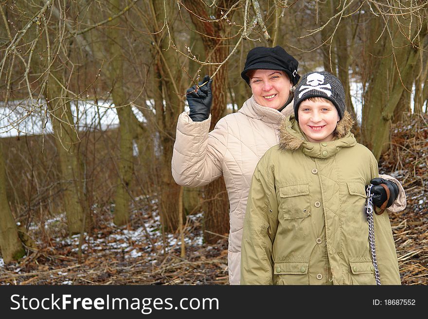 Happy mother and son walking in the winter forest