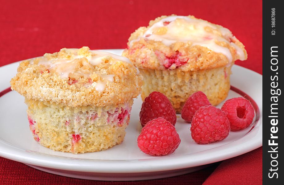 Two raspberry muffins with raspberry fruit on a plate