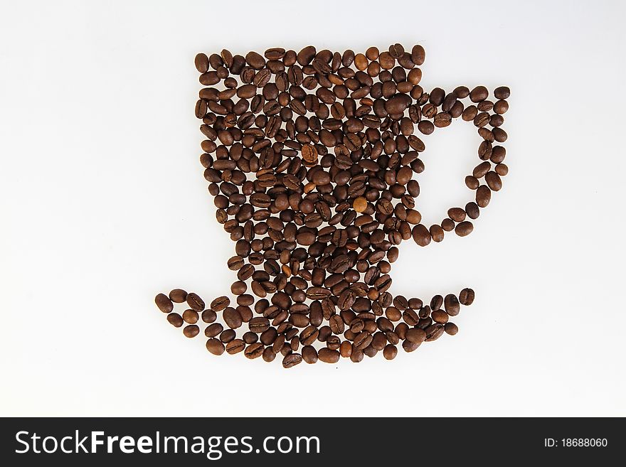 Roasted beans gathered in a shape of coffee cup on the white background