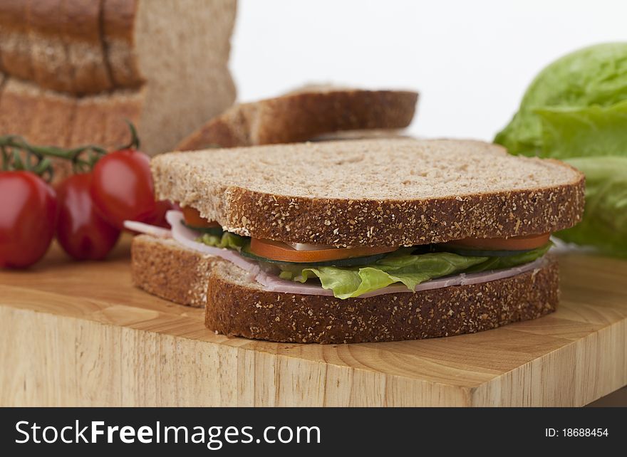 Freshly made ham and salad sandwich on a cutting board surrounded by its ingredients. Freshly made ham and salad sandwich on a cutting board surrounded by its ingredients