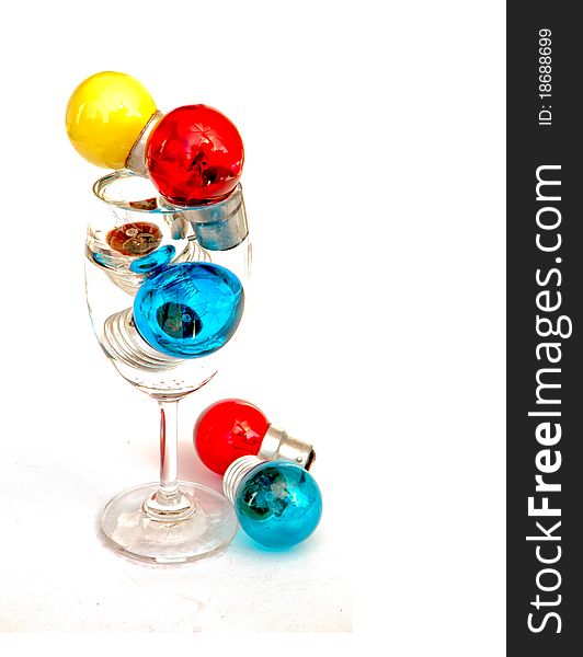 Many colors light bulb in wine glass isolated on white background. Many colors light bulb in wine glass isolated on white background.