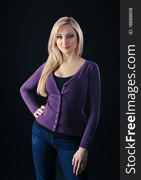 Portrait of beauty blonde girl in lilac top and jeans on black background. Portrait of beauty blonde girl in lilac top and jeans on black background