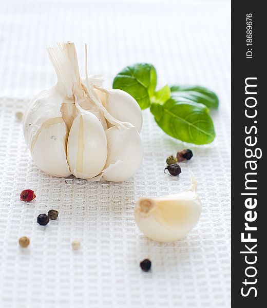 Fresh garlic with pepper and basil on kitchen towel