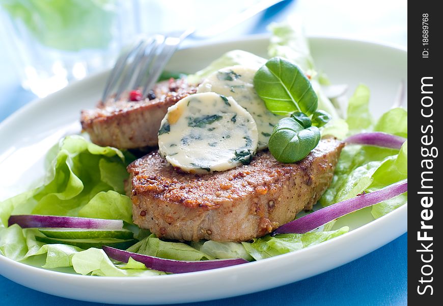 Juicy fillet steak with butter with fresh basil and peppercorns, lettuce and onion