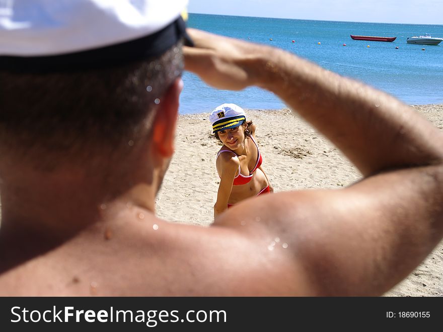 Beautiful young woman in a red swimsuit plays with a young sailor's desires and temps him to come to the sea. Beautiful young woman in a red swimsuit plays with a young sailor's desires and temps him to come to the sea.