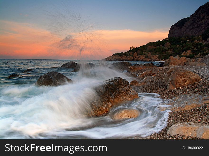 Waves crash on a rock in the dawn on the ocean coast. Waves crash on a rock in the dawn on the ocean coast