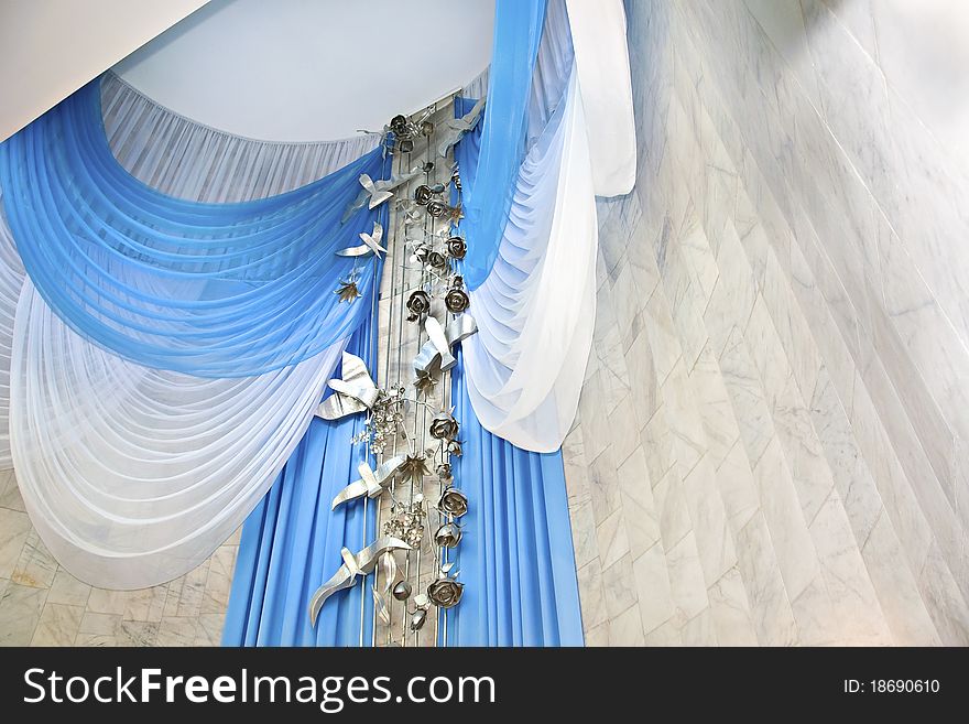 From the ceiling of the hall a solemn marriage down the white and blue curtains decorating the room. From the ceiling of the hall a solemn marriage down the white and blue curtains decorating the room