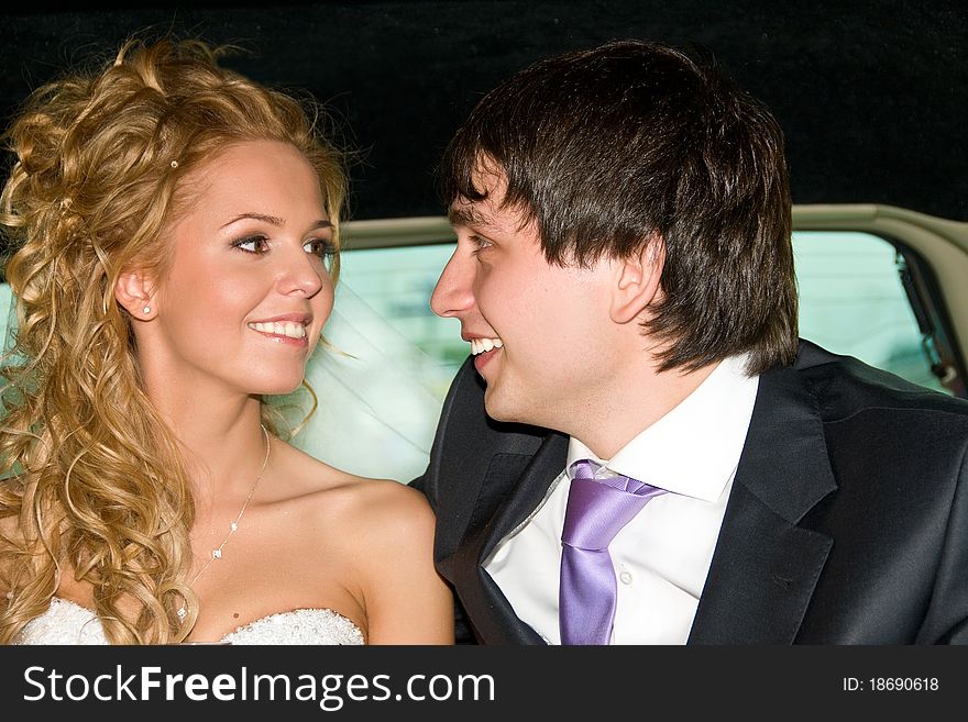 The bride and groom in a wedding limousine look into each others eyes and smiling with happiness. The bride and groom in a wedding limousine look into each others eyes and smiling with happiness