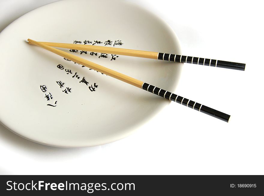 Chopsticks on a round plate with hieroglyphs.