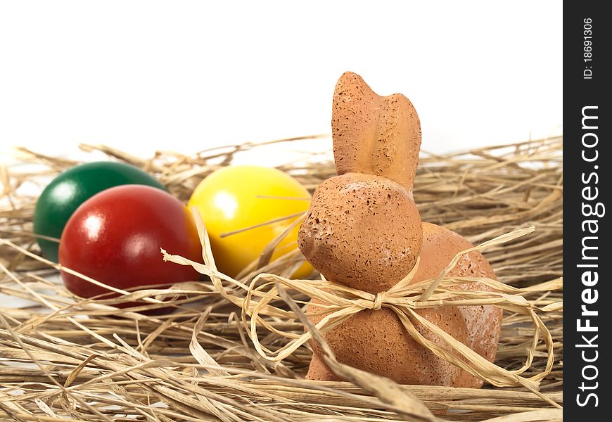 Easter Rabbit with three eggs in the background standing on straw. Easter Rabbit with three eggs in the background standing on straw