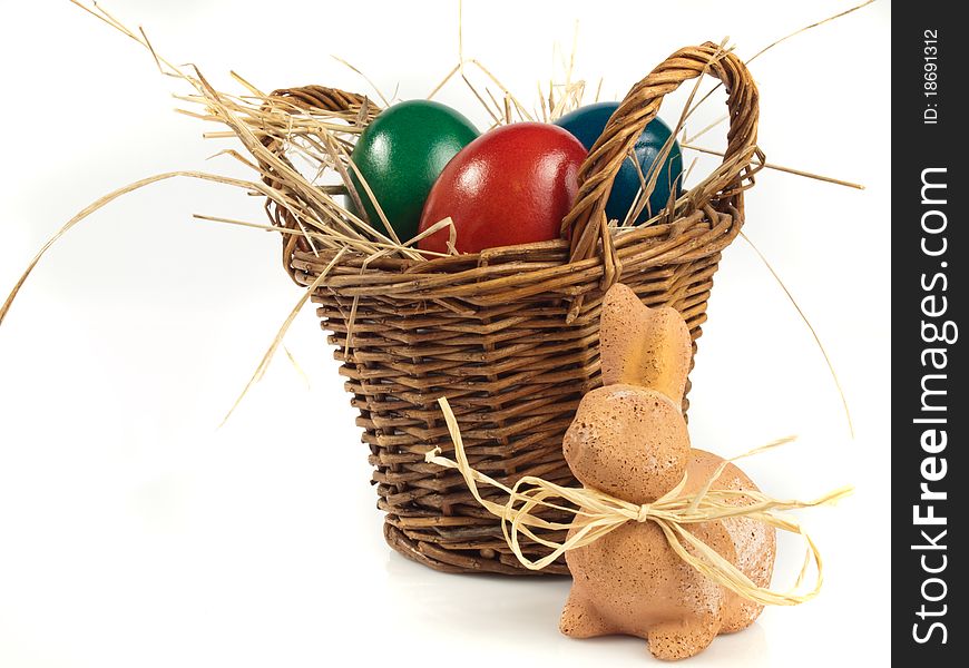 Easter Rabbit in front of a basket with three easter eggs. Easter Rabbit in front of a basket with three easter eggs