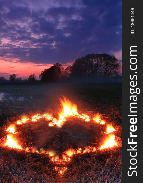 Spring fires in a field at sunset