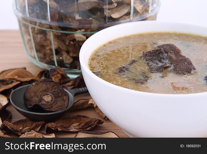Mushroom soup in a bowl with dried mushrooms surrounding it and some in a jar, and an antique spoon. Mushroom soup in a bowl with dried mushrooms surrounding it and some in a jar, and an antique spoon