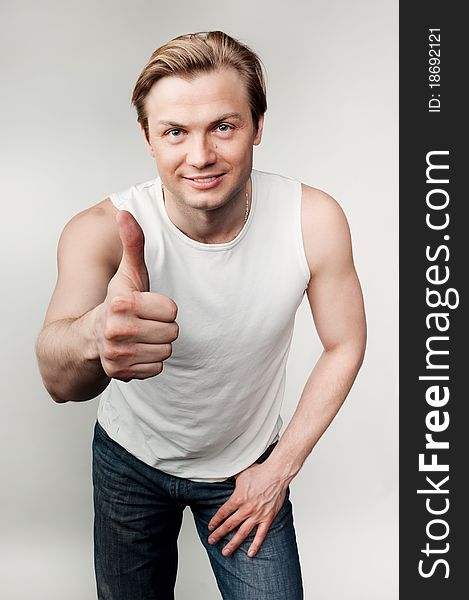 Young man with thump up on the gray background. Young man with thump up on the gray background