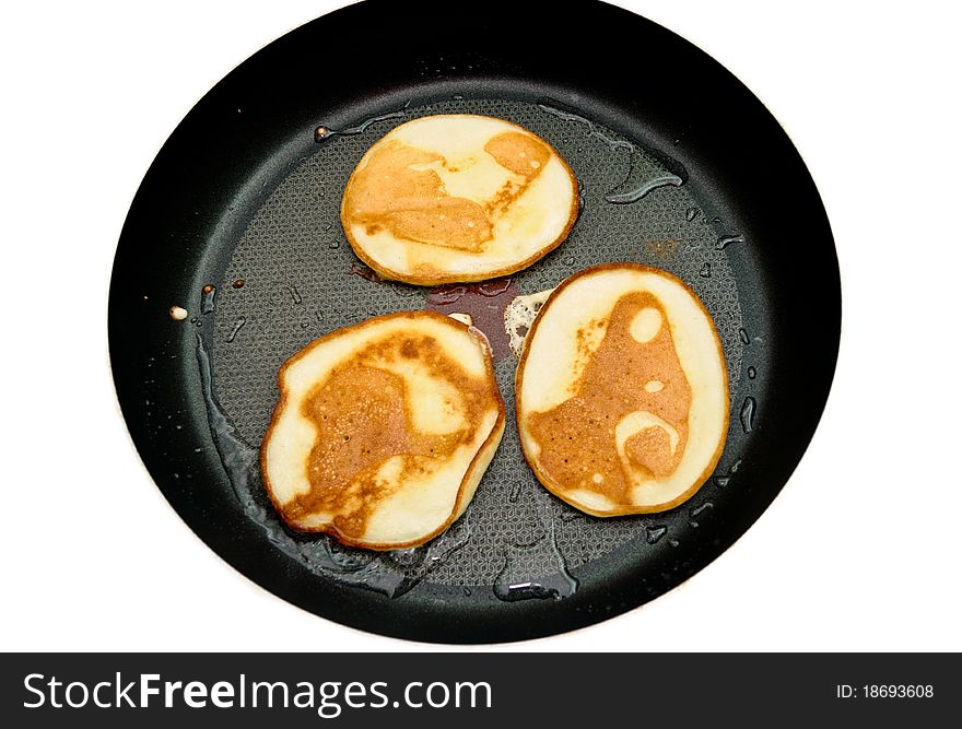 Fritters on a frying pan pancakes on the griddle on the white isolated background