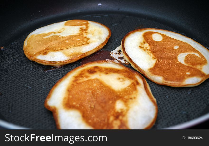 Fritters on a frying pan pancakes on the griddle on the white isolated background